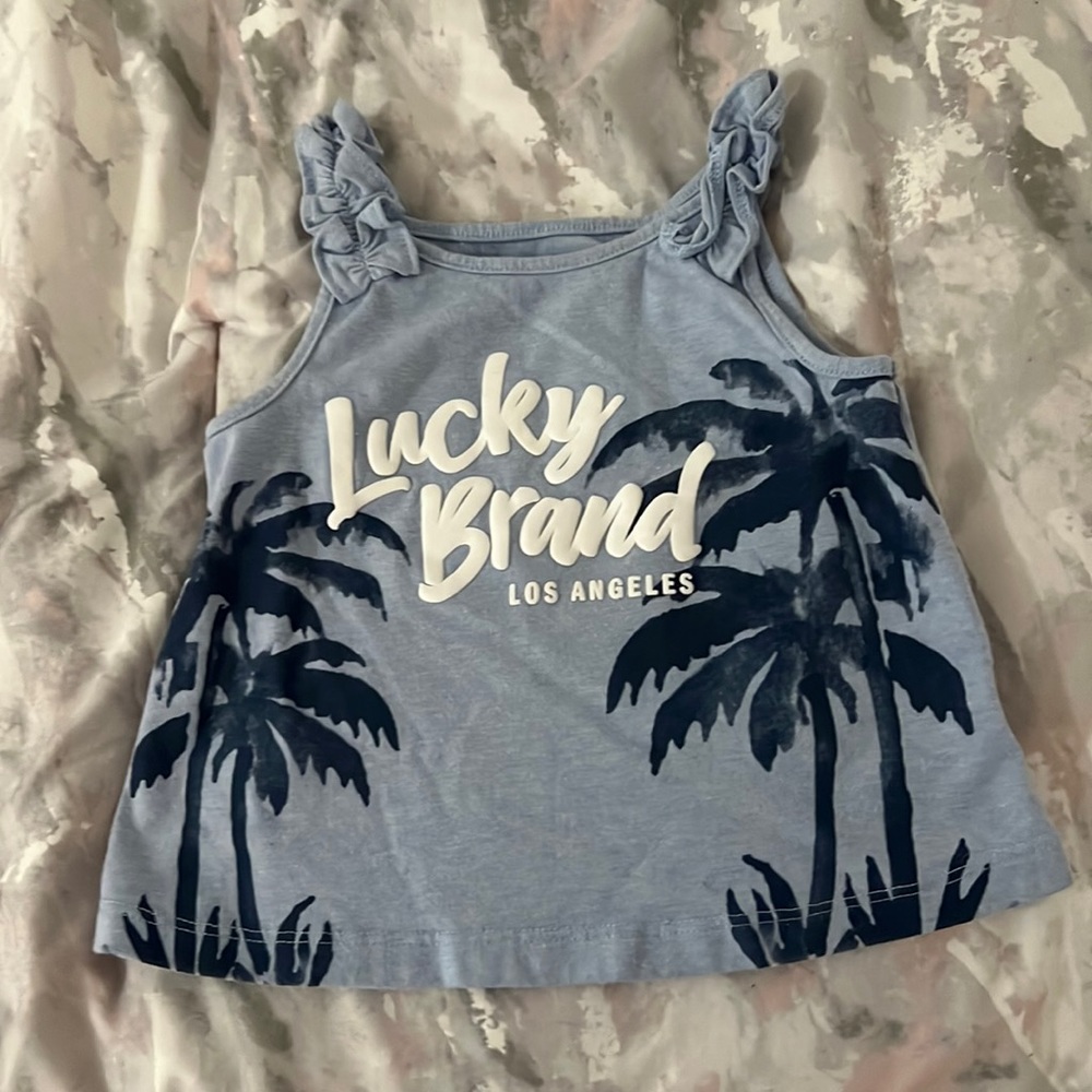 A girl tank top blue with Palm trees on it and saying Lucky Brand Los Angeles